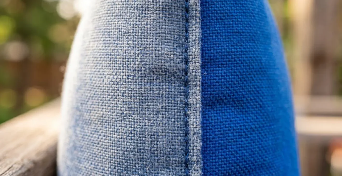 Gros plan sur un coussin de salon de jardin montrant le contraste entre une zone décolorée exposée au soleil et une zone encore vive protégée sous l'accoudoir