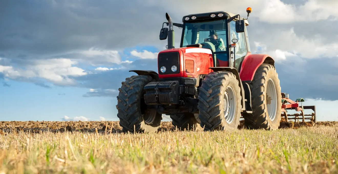 Agriculteur notant des informations de maintenance dans un carnet terrain à côté de son tracteur